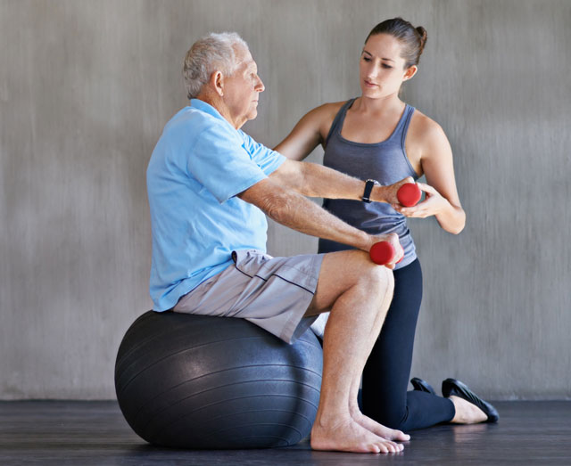 Ederly Man With Trainer and Exercise Ball Photo