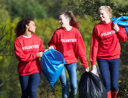 Three young women volunteer withh trash pick up in the park photo